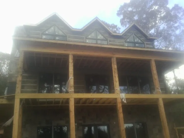 Dormers and porch framing on a large log home under construction — Roof Coating work by our crew in Maynard