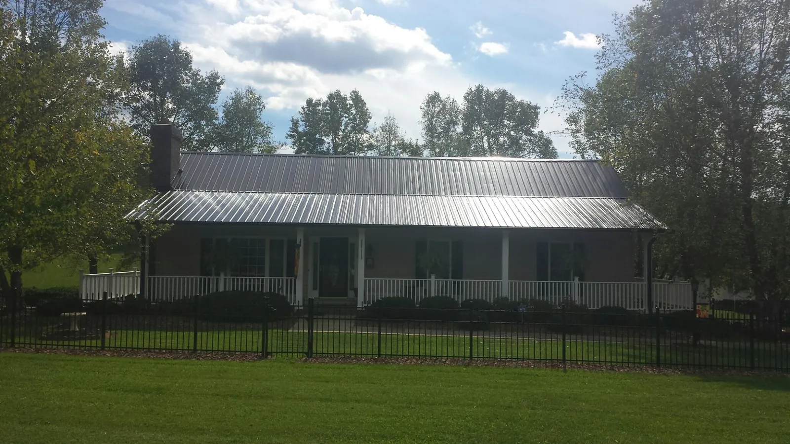 Gray metal roof on a brick ranch with a full width front porch — Gutter Guard Installation work by our crew in Maynard