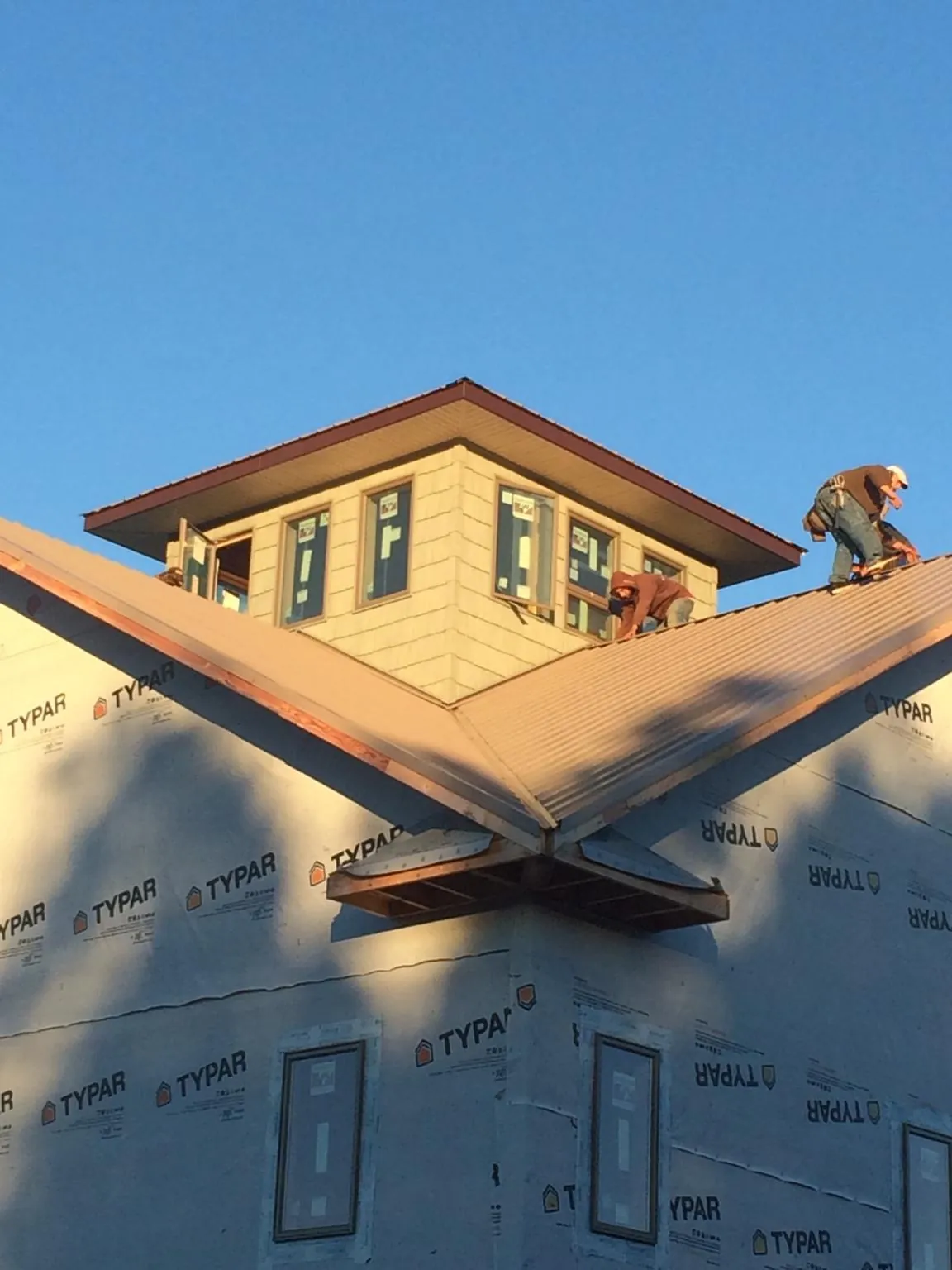Roofers working around a rooftop cupola on a new metal roof at sunset — Roof Waterproofing in Maynard by Roofing Brothers
